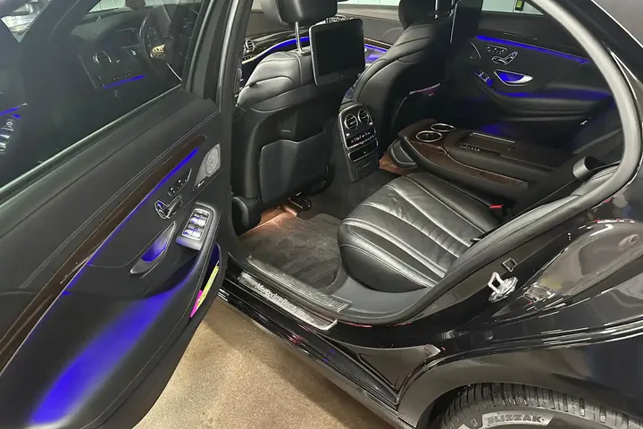 Tylna kanapa Mercedesa z ciemną tapicerką i oświetleniem kabiny.