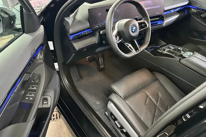 Fotel kierowcy i kokpit BMW widziane przez otwarte drzwi.