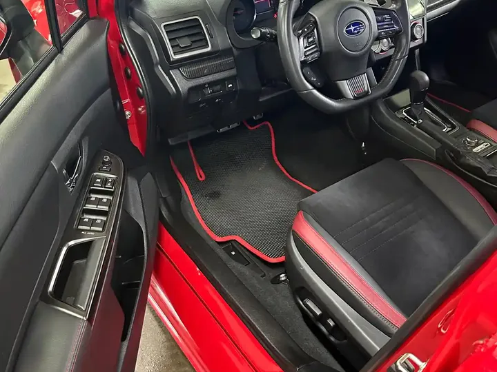 Kabina Subaru z ciemnym fotelem i czerwonymi detalami.