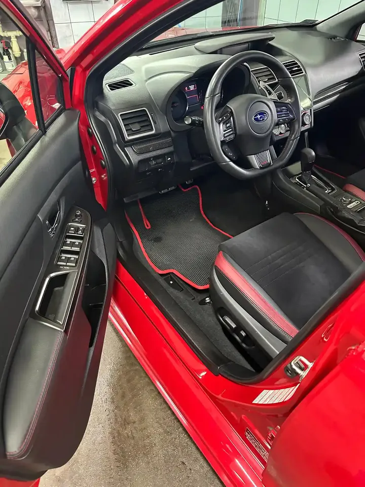 Kabina Subaru z ciemnym fotelem i czerwonymi detalami.