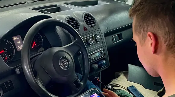 Mechanik odczytuje dane z testera diagnostycznego w kabinie samochodu.