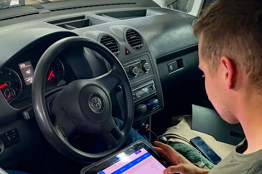 Mechanik odczytuje dane z testera diagnostycznego w kabinie samochodu.