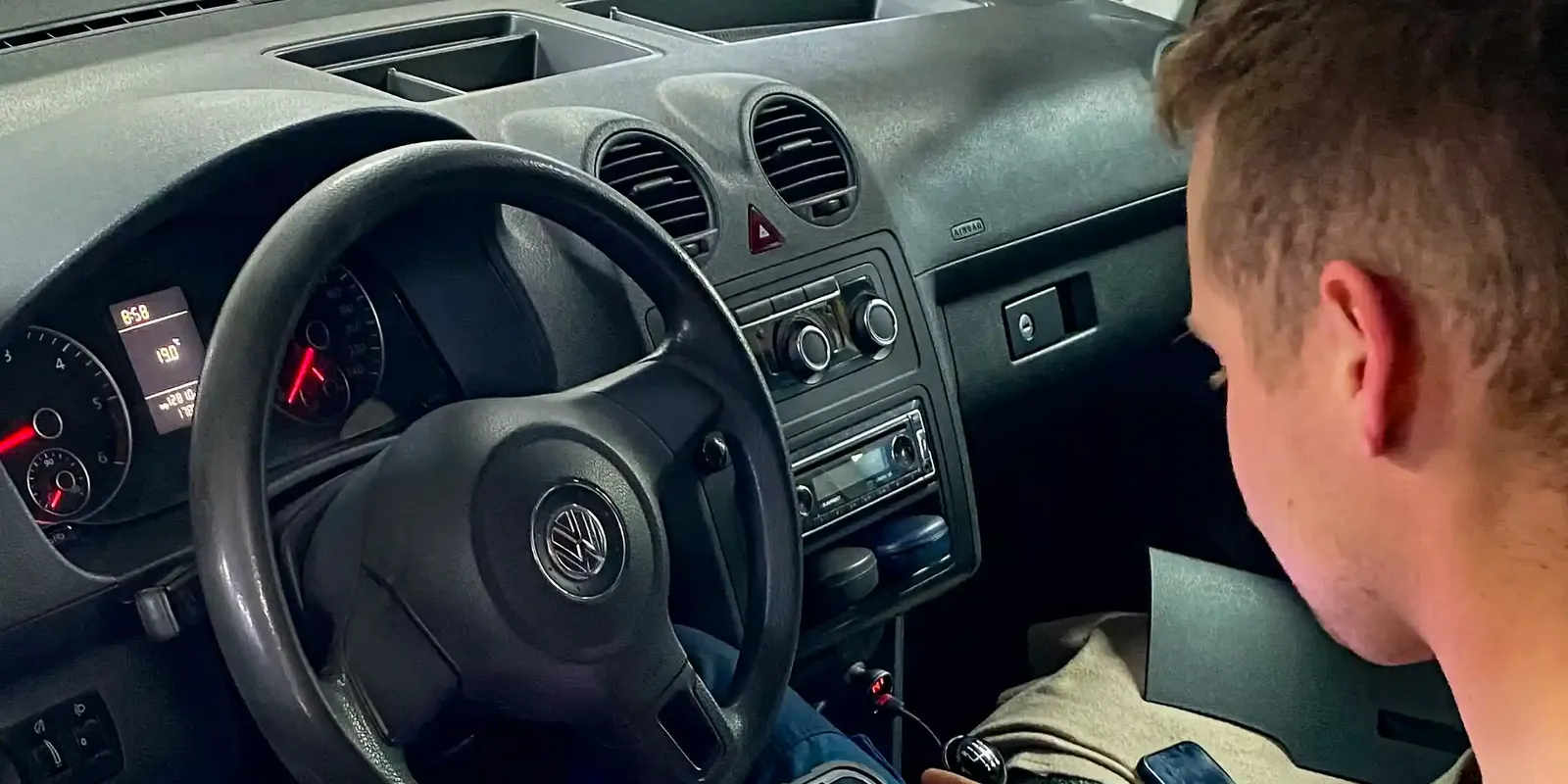 Mechanik odczytuje dane z testera diagnostycznego w kabinie samochodu.