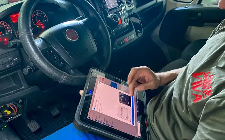 Mechanik z testerem diagnostycznym w kabinie samochodu dostawczego.