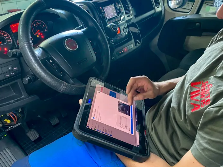 Mechanik z testerem diagnostycznym w kabinie samochodu dostawczego.