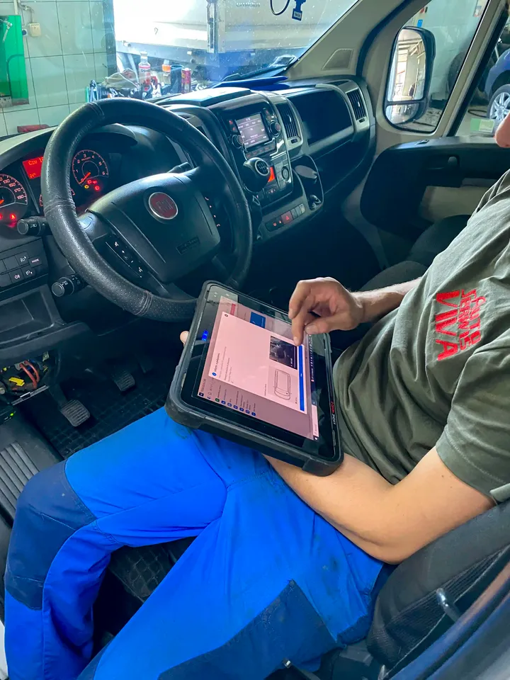 Mechanik z testerem diagnostycznym w kabinie samochodu dostawczego.