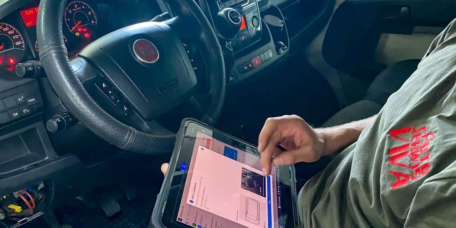 Mechanik z testerem diagnostycznym w kabinie samochodu dostawczego.