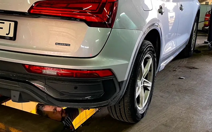 Srebrne Audi widziane od tyłu na stanowisku z podnośnikiem.
