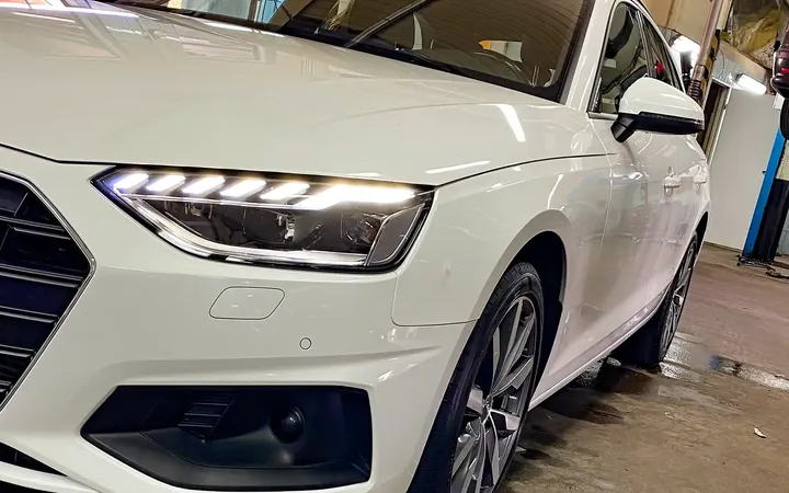 Białe Audi na stanowisku warsztatowym z przodu.