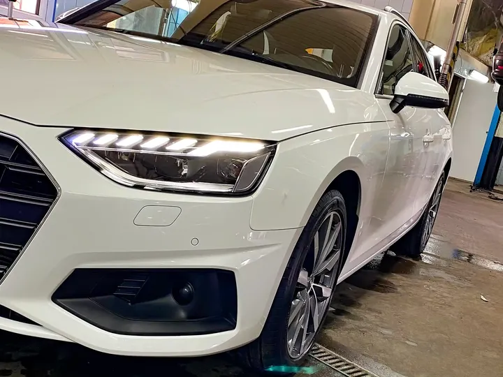 Białe Audi na stanowisku warsztatowym z przodu.