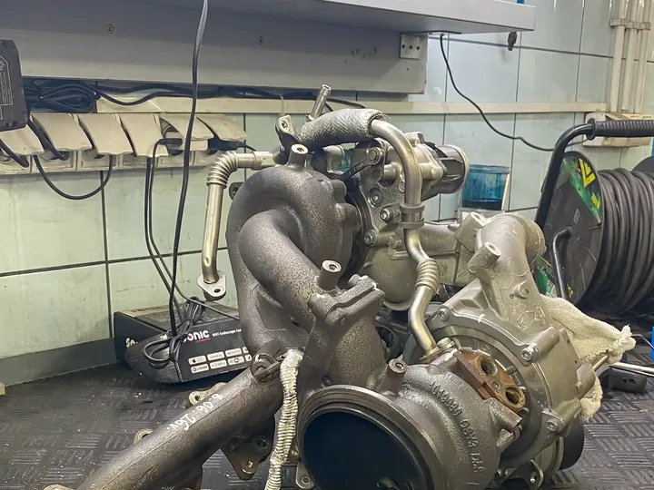 Wymontowana turbosprężarka z elementami zespołu na stole warsztatowym.