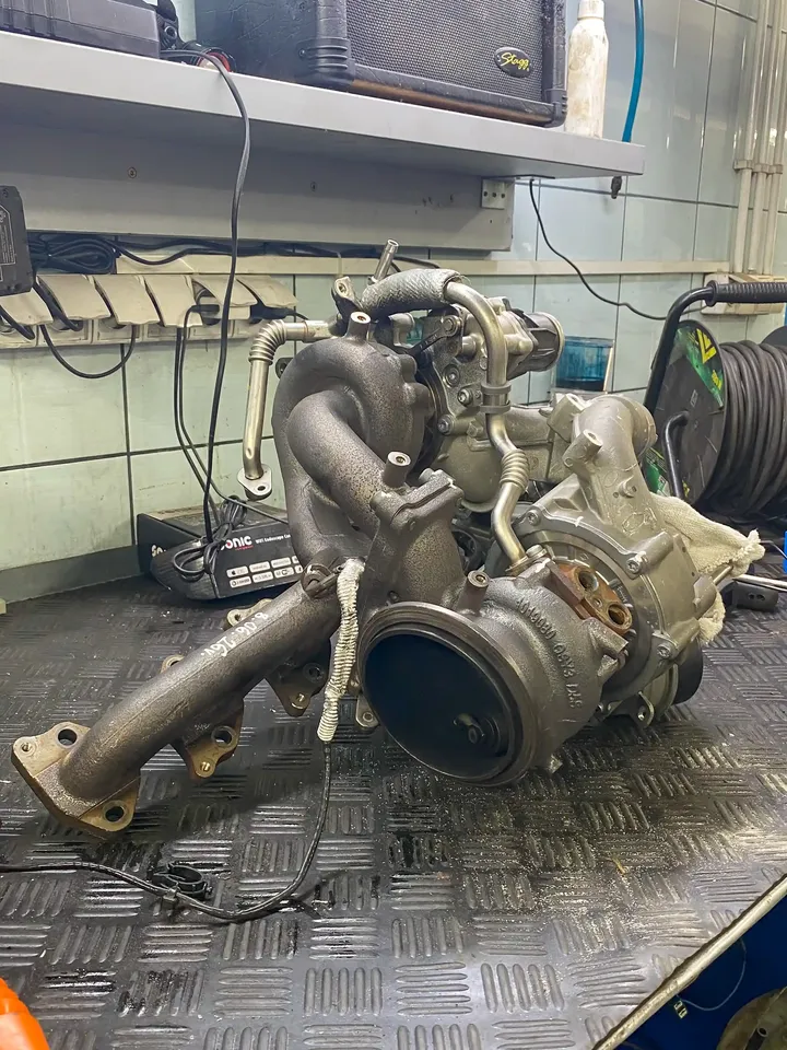 Wymontowana turbosprężarka z elementami zespołu na stole warsztatowym.