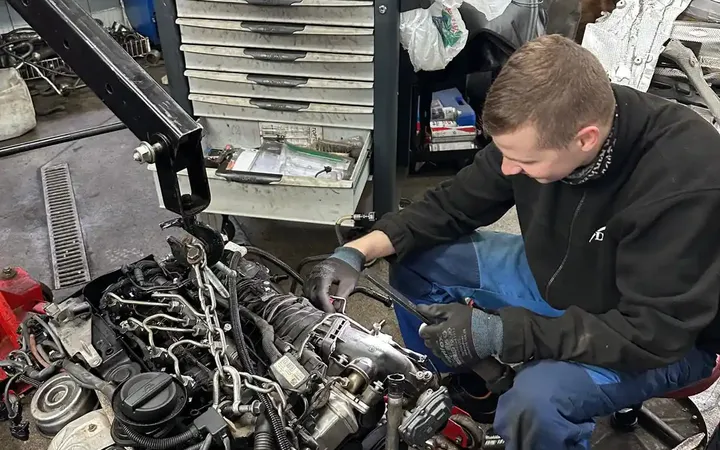 Mechanik pracuje przy silniku wyjętym z samochodu.