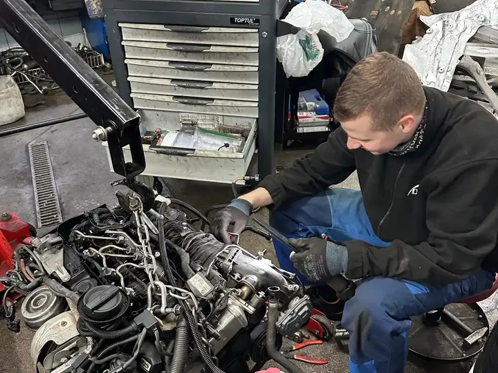 Mechanik pracuje przy silniku wyjętym z samochodu.