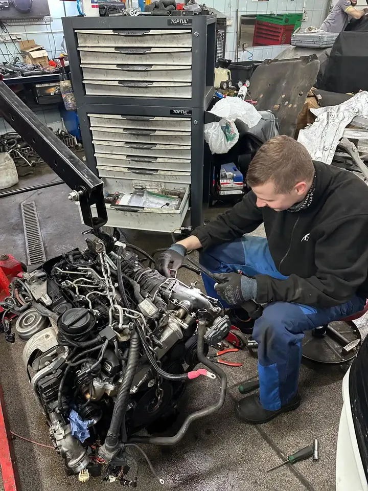 Mechanik pracuje przy silniku wyjętym z samochodu.