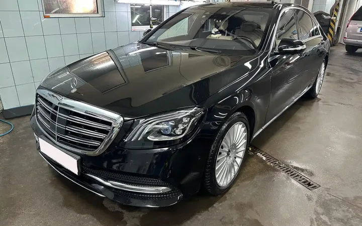 Czarny Mercedes we wnętrzu warsztatu samochodowego.