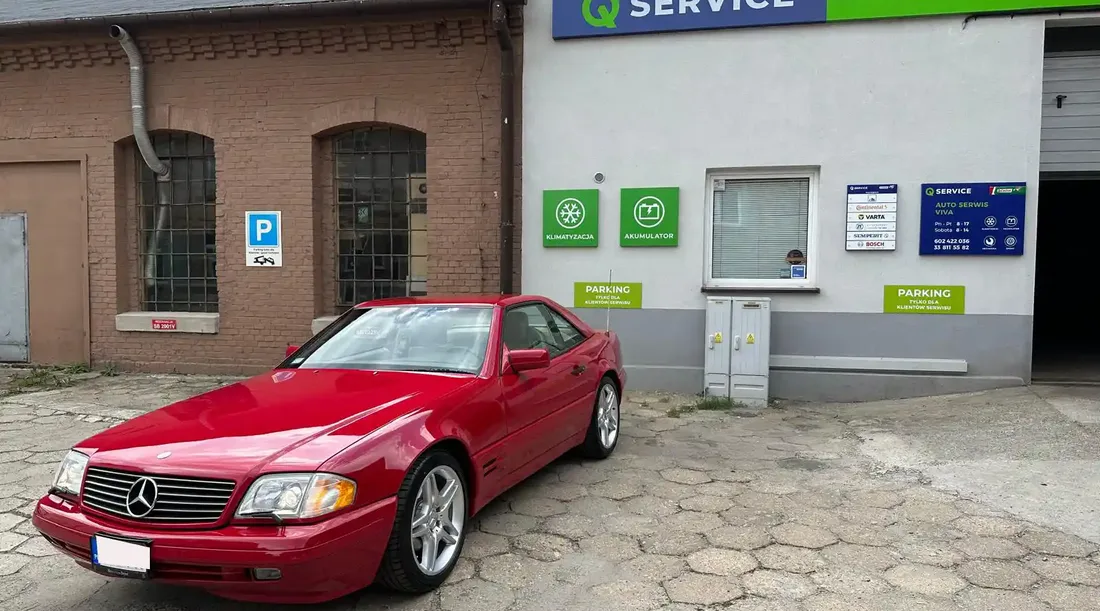 Budynek Auto Serwis VIVA z szyldem Q Service i czerwonym Mercedesem przed wejściem.
