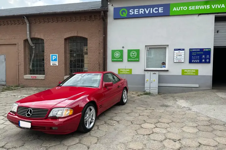 Budynek Auto Serwis VIVA z szyldem Q Service i czerwonym Mercedesem przed wejściem.