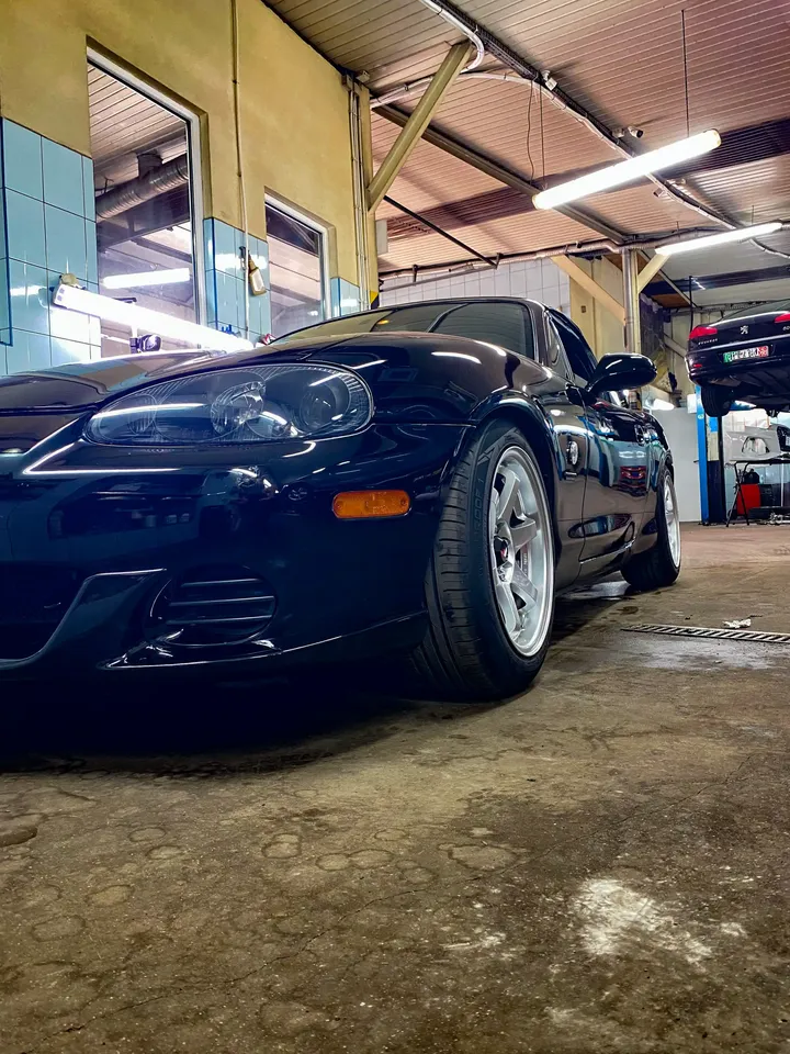 Ciemna Mazda MX-5 widziana od przodu w hali warsztatu.