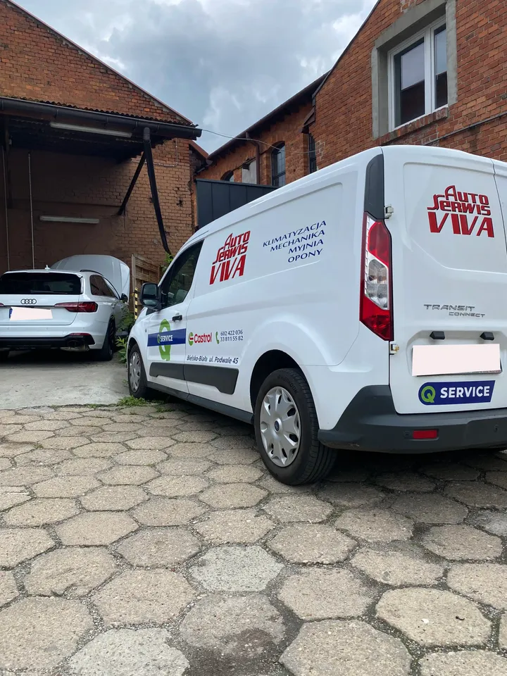 Oznakowany samochód Auto Serwis VIVA na placu przy warsztacie.