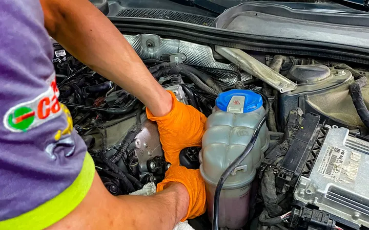 Mechanik w rękawicach pracuje przy otwartej komorze silnika.