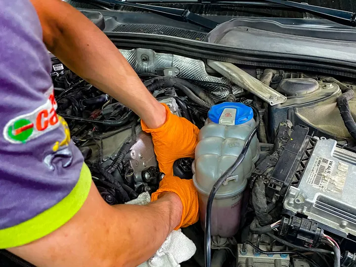 Mechanik w rękawicach pracuje przy otwartej komorze silnika.