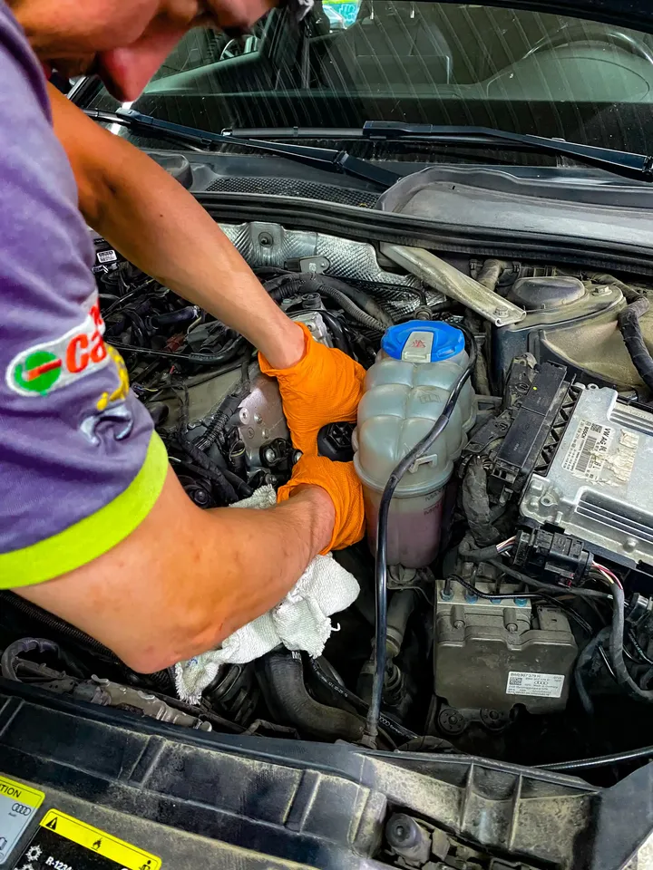 Mechanik w rękawicach pracuje przy otwartej komorze silnika.