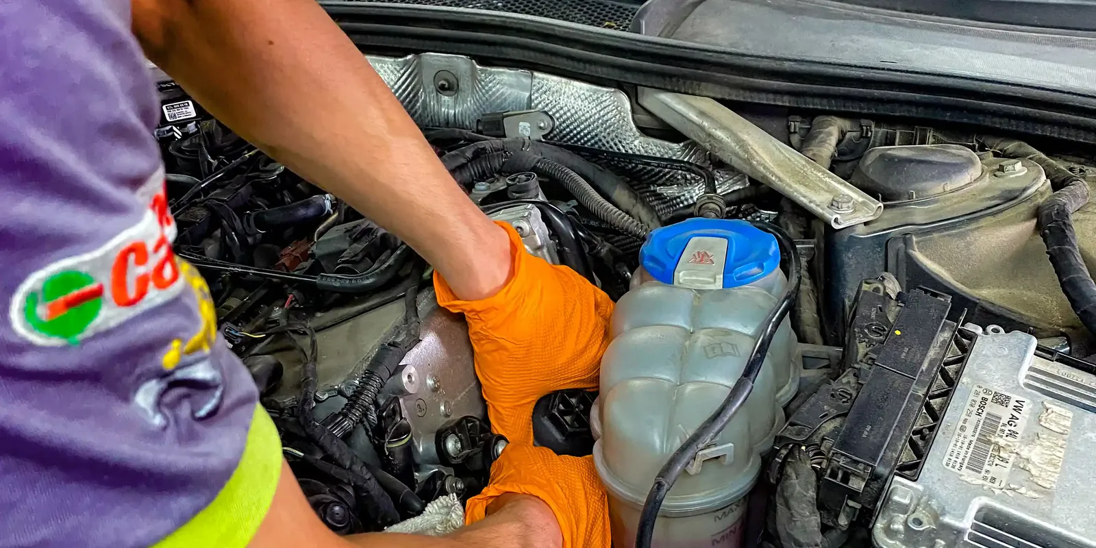 Mechanik w rękawicach pracuje przy otwartej komorze silnika.
